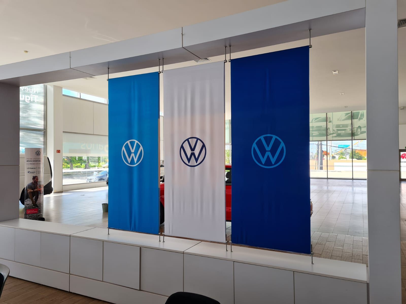 Banderas colgantes de marca instaladas en showroom automotriz en Cancún